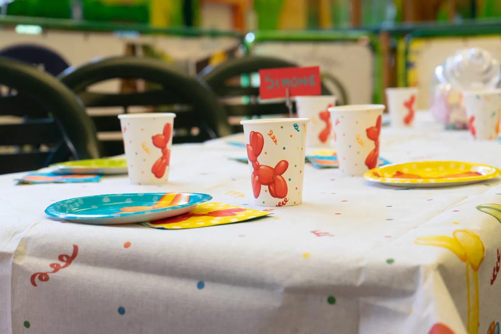 Un tavolo apparecchiato per la festa, con i bicchieri e i piatti colorati