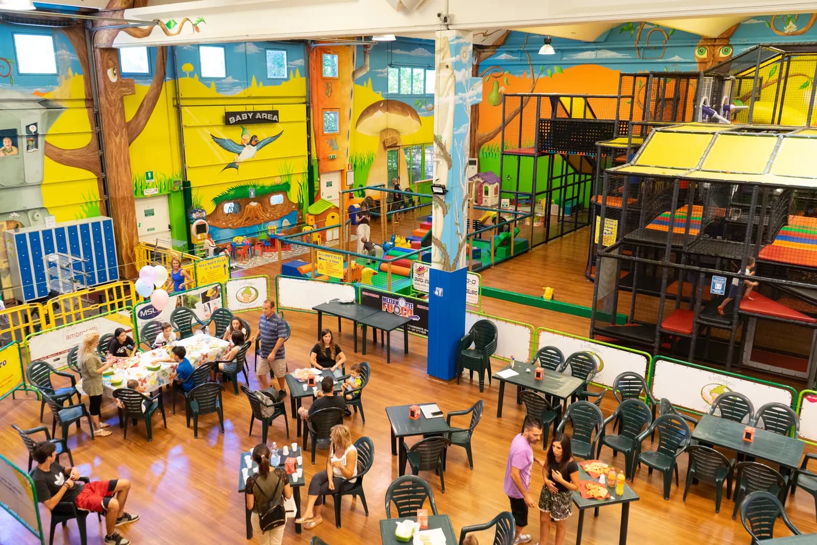 La sala del ristorante con i tavoli occupati e il parco giochi sullo sfondo