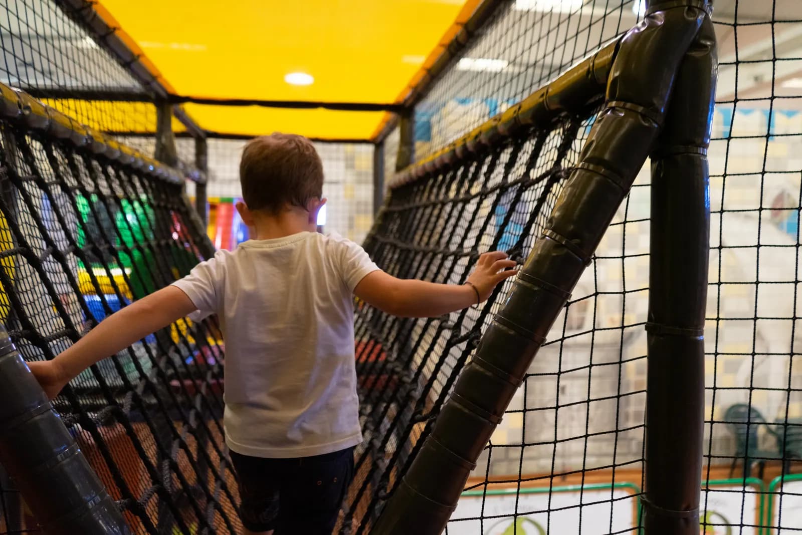 Un bambino di spalle si arrampica sulla parete di rete del playground