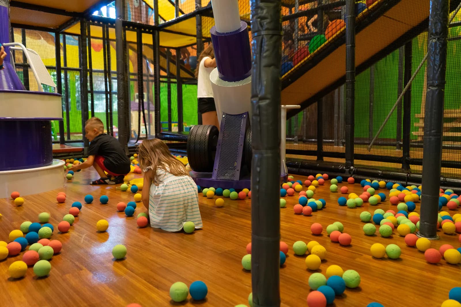 Bambini di spalle giocano tra le palline sotto i cannoni ad aria
